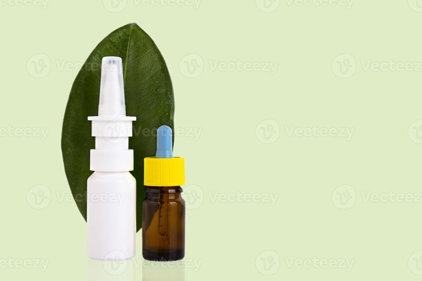 Blank amber glass essential oil bottle with pipette, nasal spray on green leaves background. photo