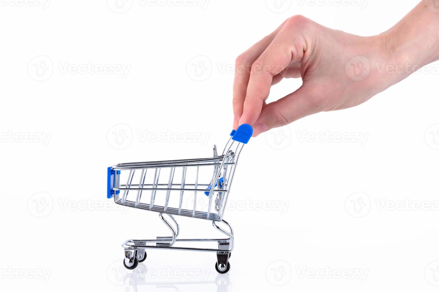 Female hand with fingers pushing a shopping cart isolated on white background. Copy space. photo