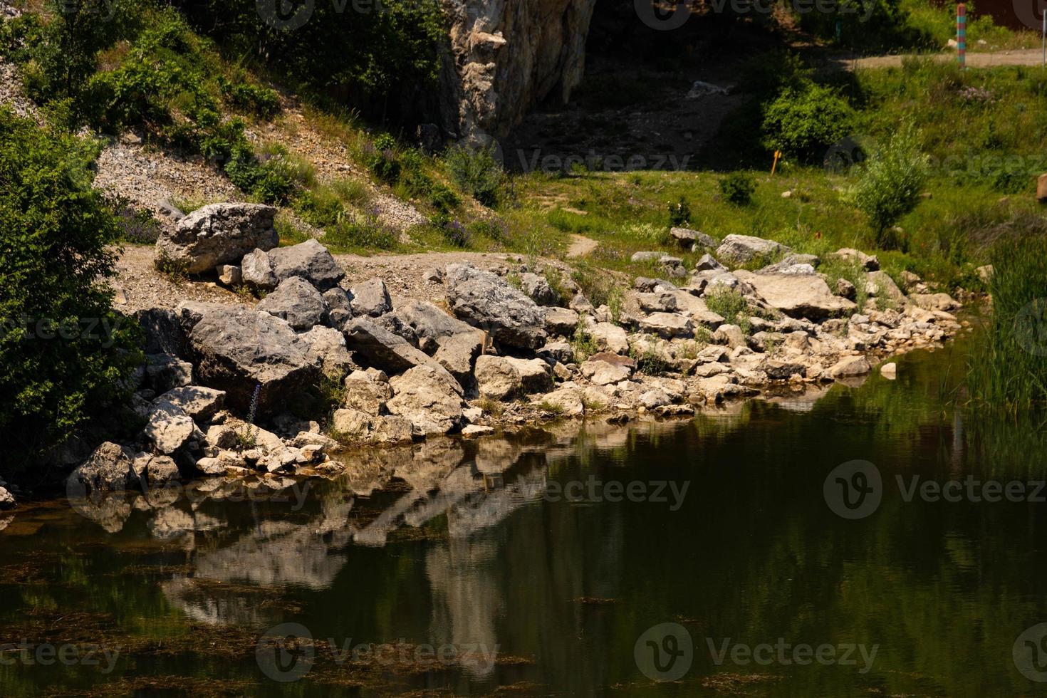 View of the coastline of a mountain lake in the foreground with large stones and reflection in the water. Scenery. photo