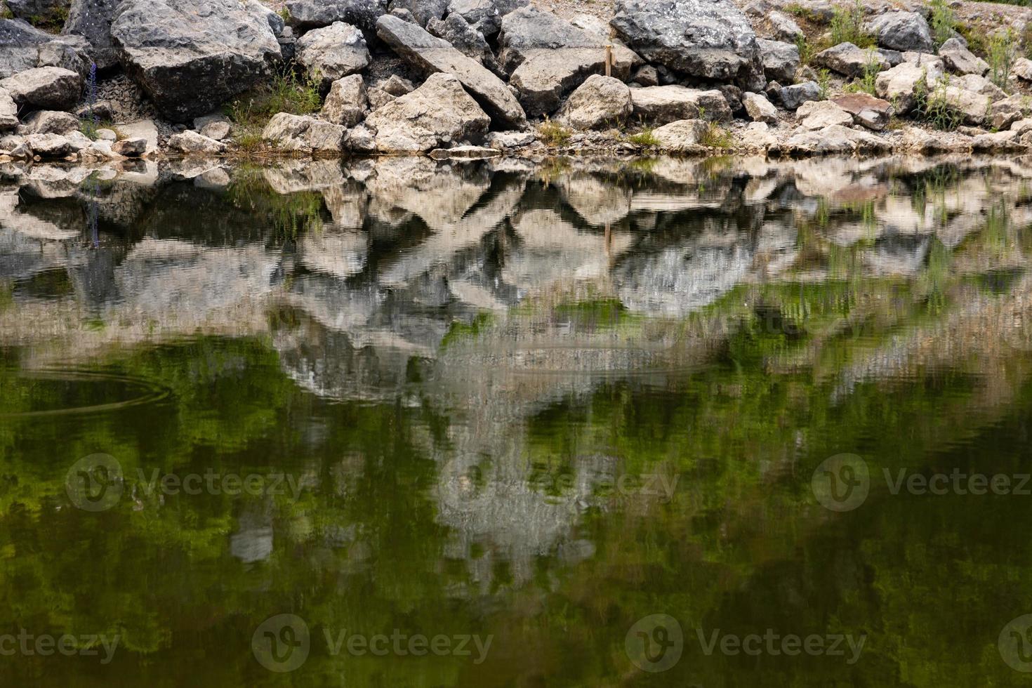 View of the coastline of a mountain lake in the foreground with large stones and reflection in the water. Scenery. photo