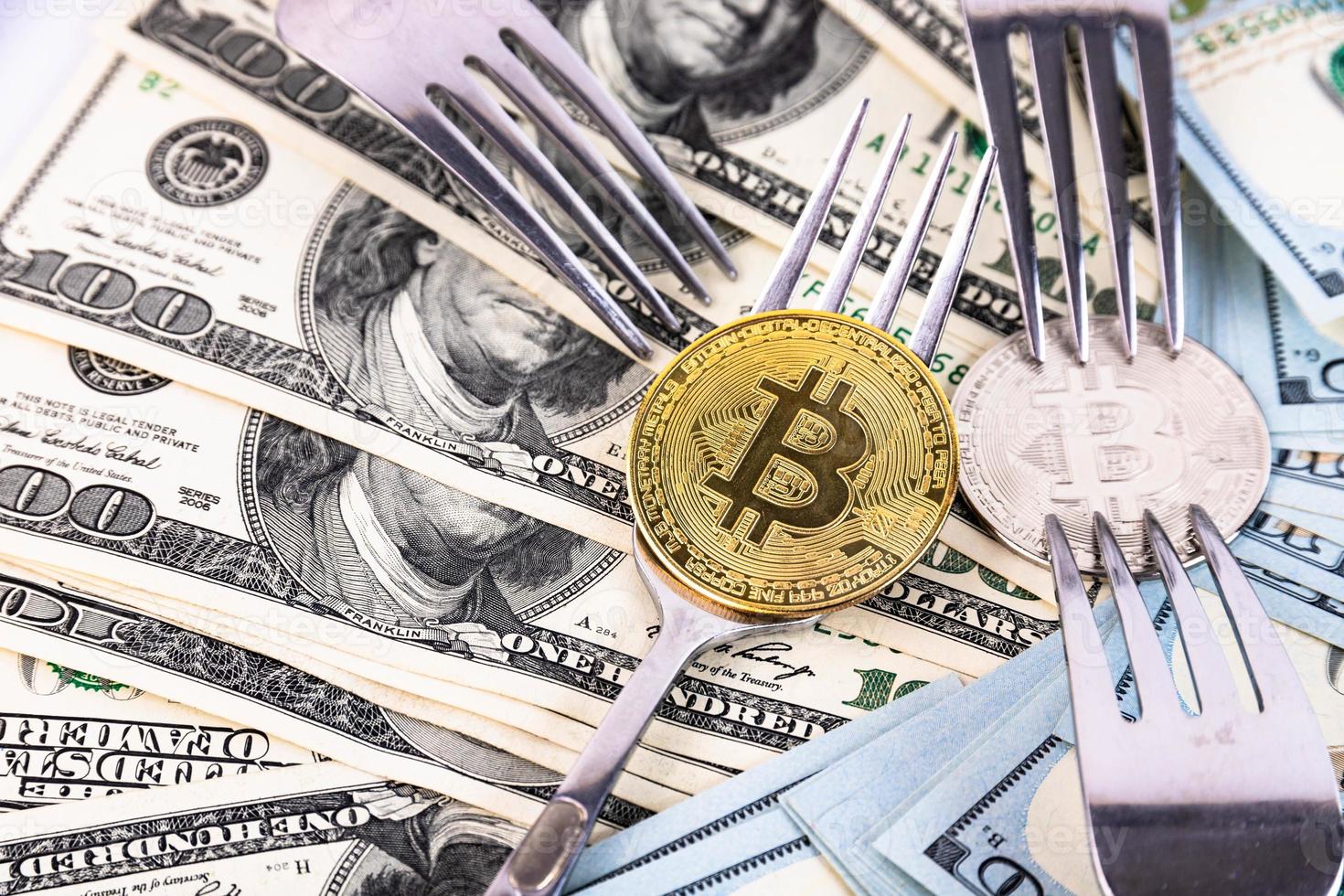 Gold bitcoin on the background of one hundred dollar bills and cutlery. photo