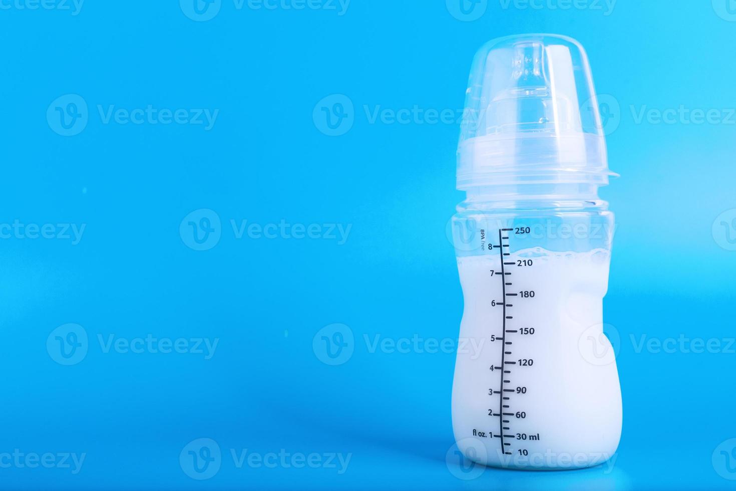 Baby feeding bottle with pacifier on blue background. Copy space. photo