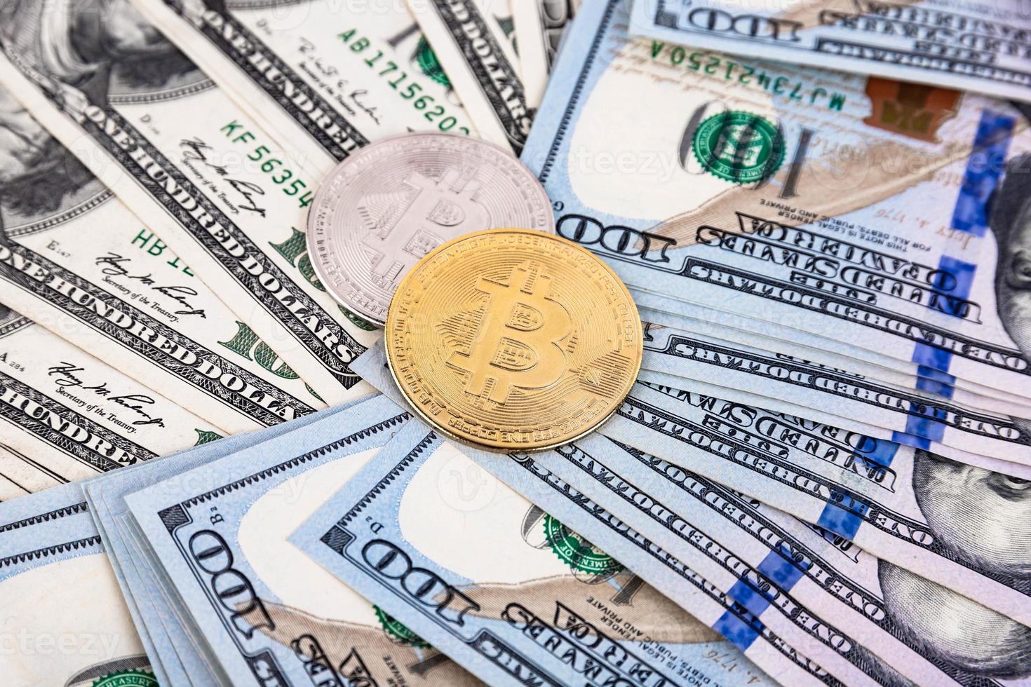 Platinum and gold bitcoin on the background of one hundred dollar bills photo