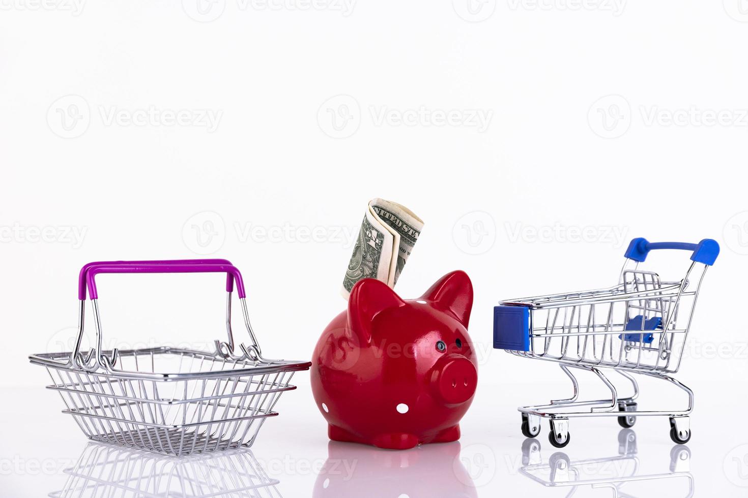 Red piggy bank with money and empty shopping baskets. Copy space. Selective focus. photo