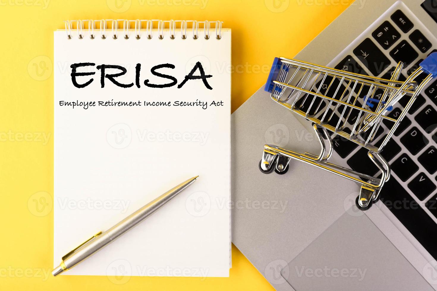 A paper with the ERISA Employee Pension Law on lies on a table with a laptop, on a yellow background. Flat lay. photo