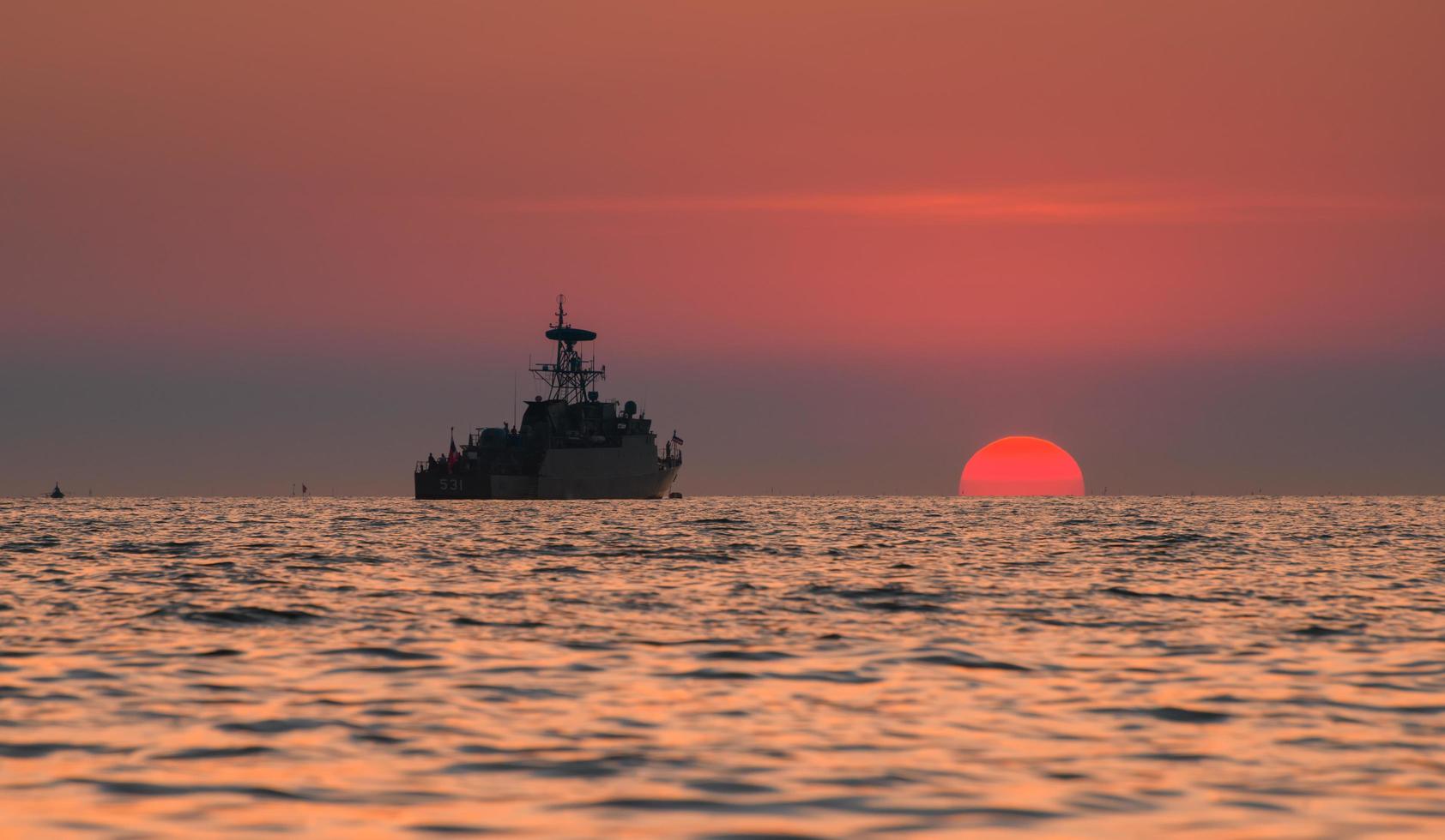 Silhouette military war ship and the sun. photo