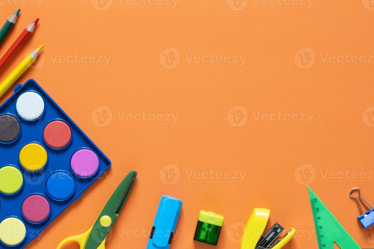 Back to school concept. School and office supplies on the office table. Orange background.Flat lay photo