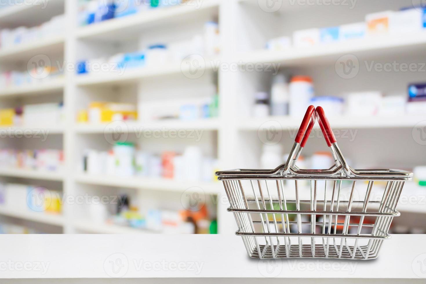 Empty shopping basket on pharmacy drugstore counter with blur shelves of medicine and vitamin supplements background photo