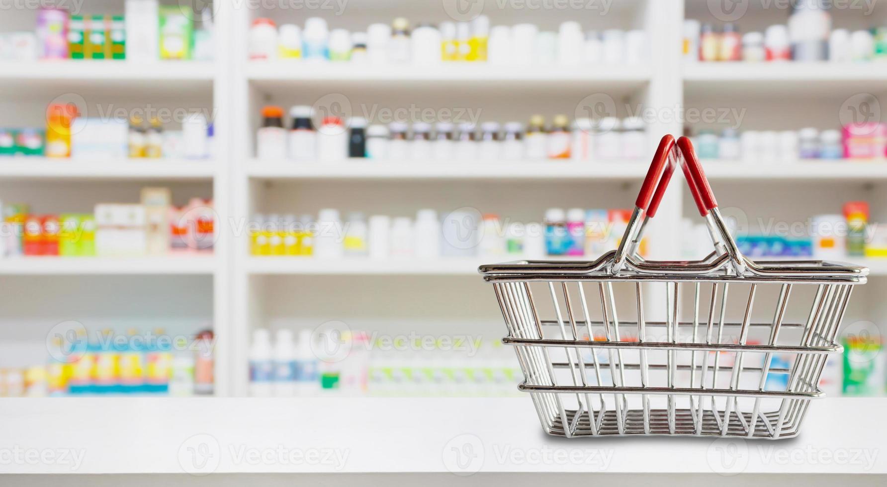 Empty shopping basket on pharmacy drugstore counter with blur shelves of medicine and vitamin supplements background photo