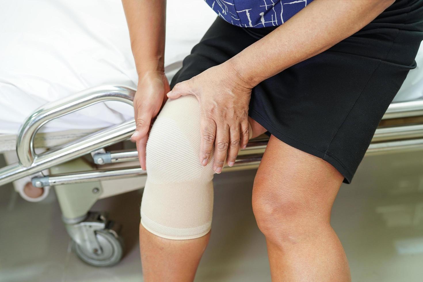 Asian senior woman wearing elastic support knee brace for reduce pain. photo