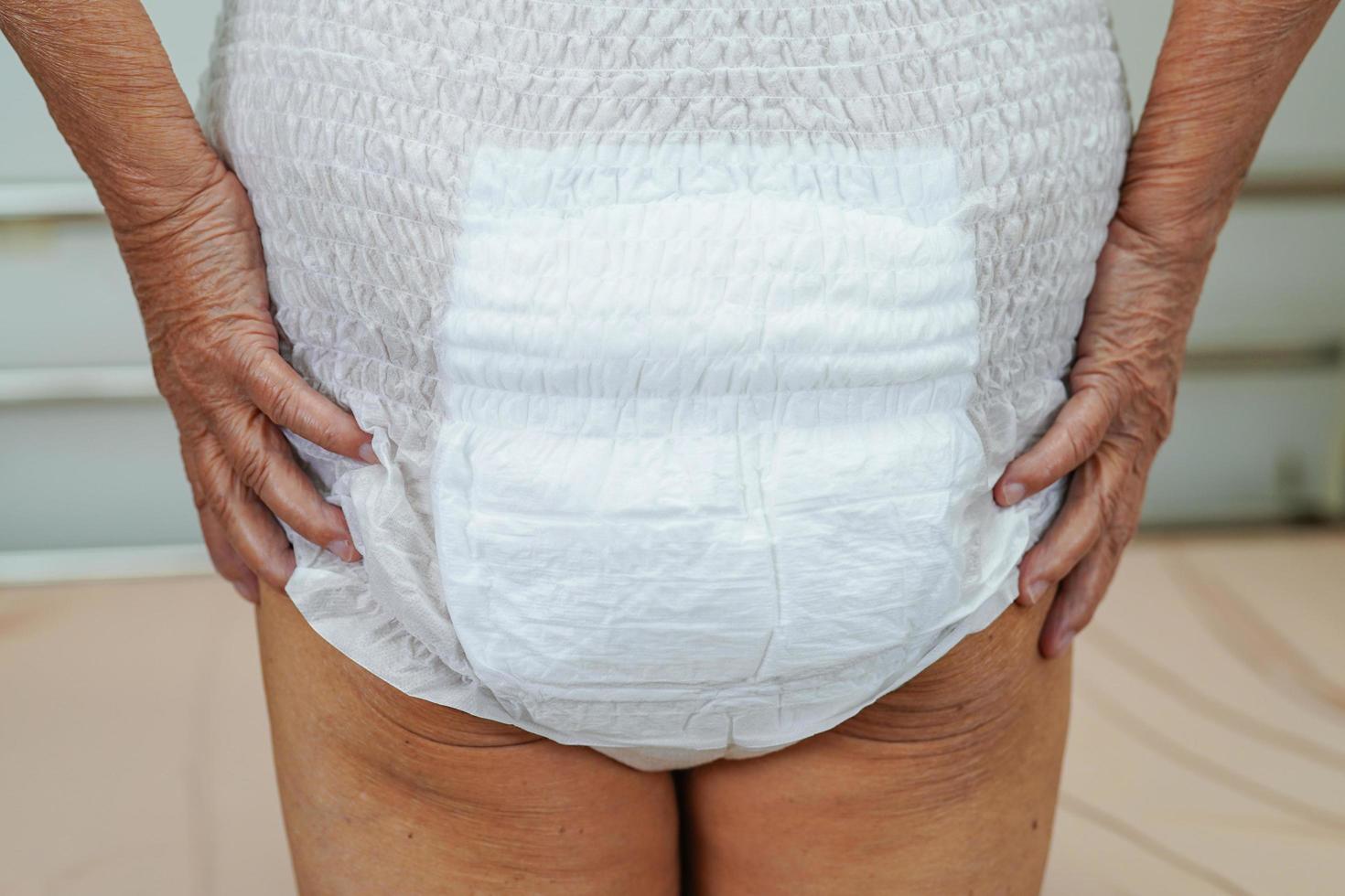 Asian elder senior woman patient wearing adult incontinence diaper pad in hospital. photo