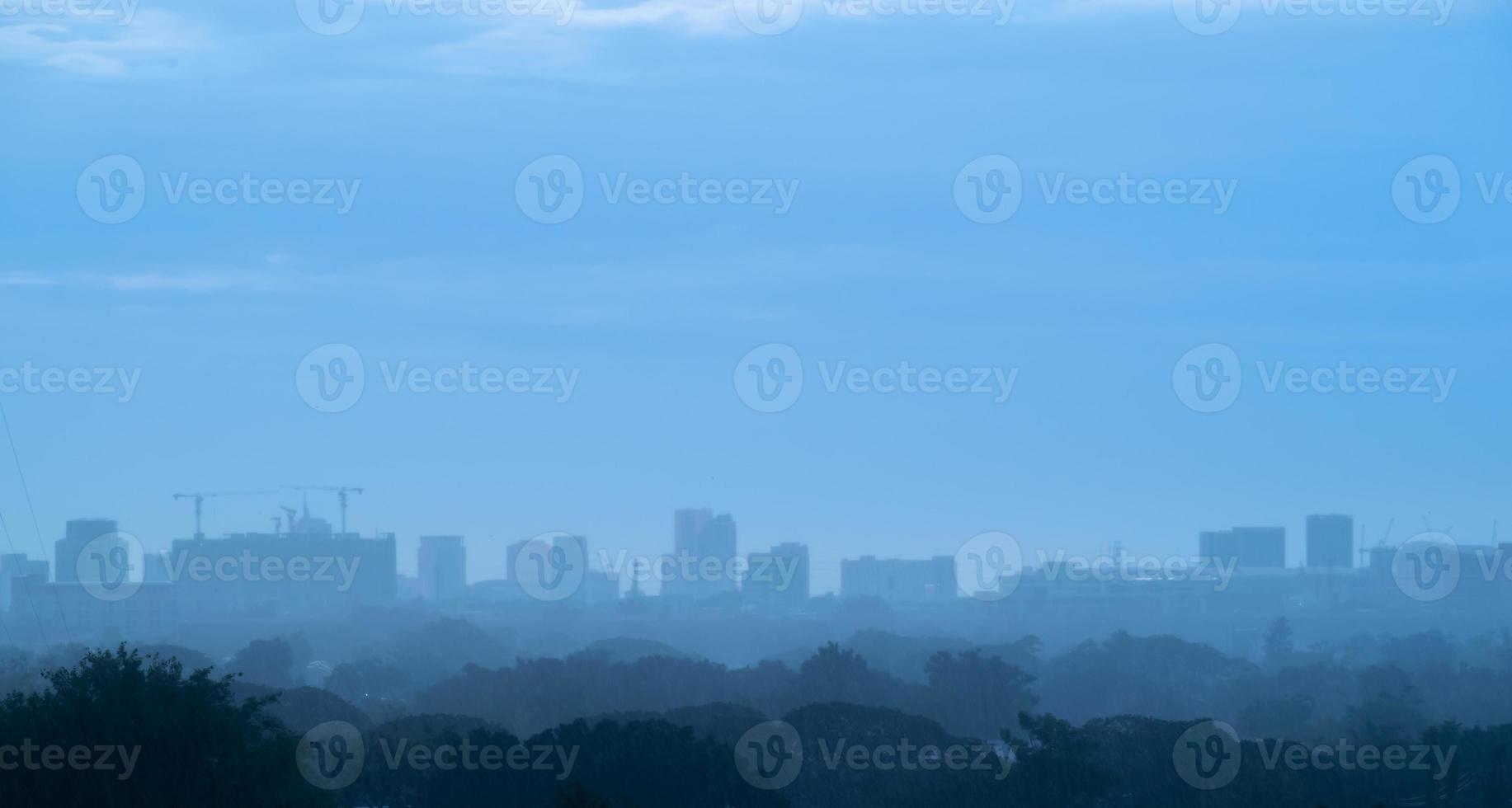 Background heavy rain falling from rainy season sky, tree and building silhouette, tropical Thailand. photo