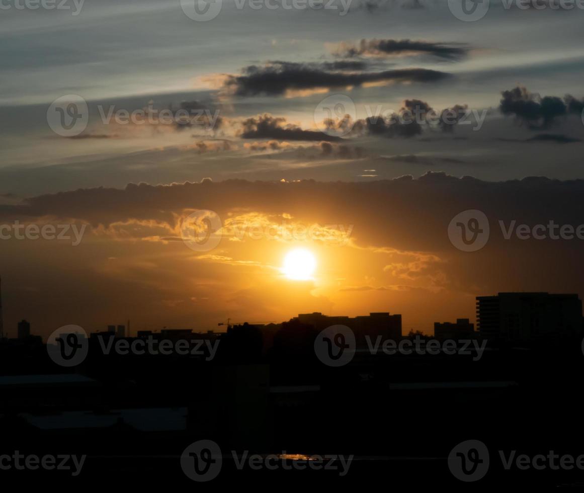 Gives a warm feeling,sunset behind the city building,silhouette city tall buildings,building silhouette again beautiful sky background and freedom concept. photo