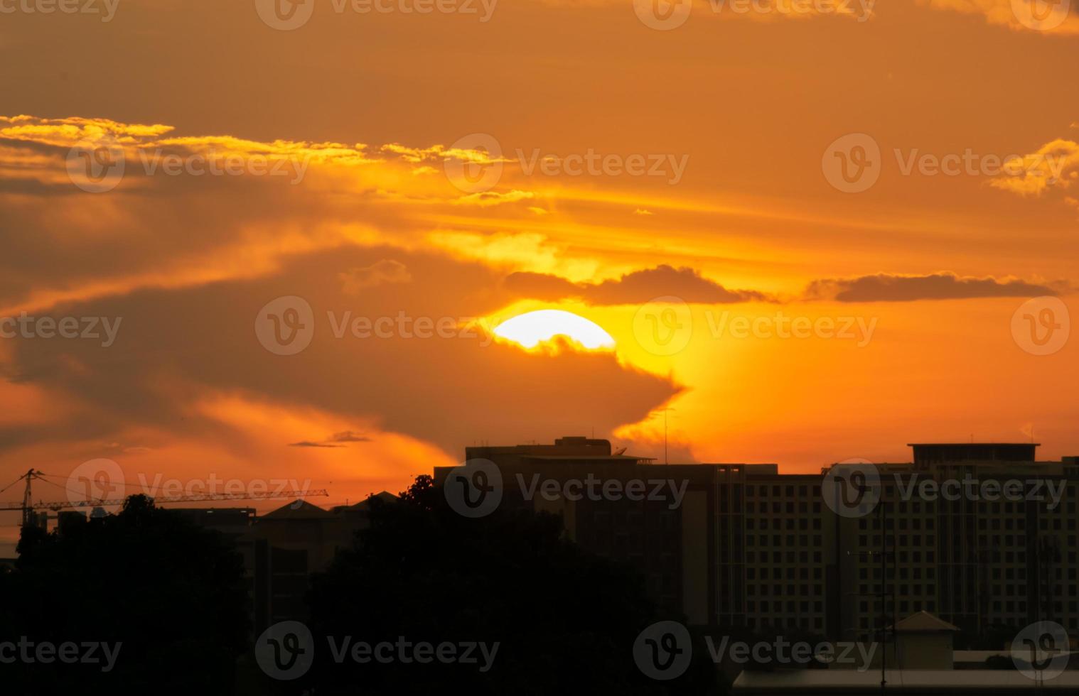 Gives a warm feeling,sunset behind the city building,silhouette city tall buildings,building silhouette again beautiful sky background and freedom concept. photo