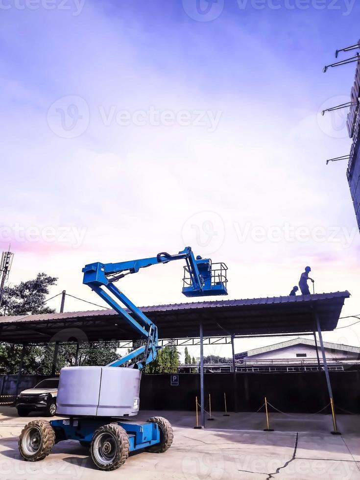 Manlift crane with platform lifting to the roof top of a building photo