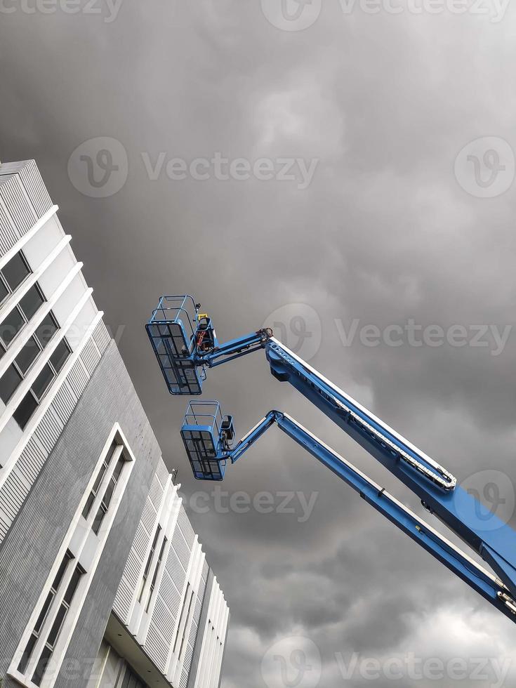 Manlift crane with platform lifting to the roof top of a building photo