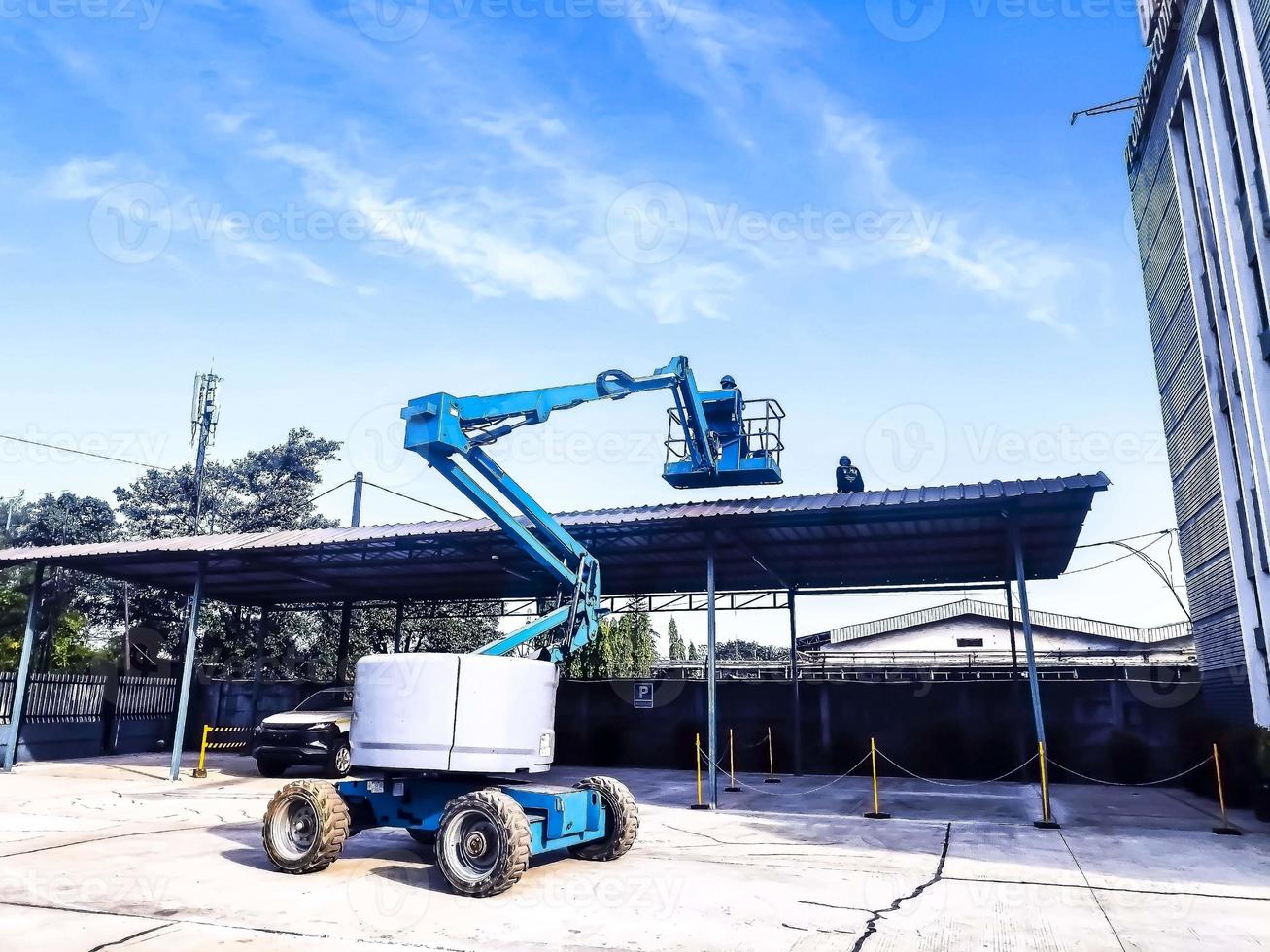 Manlift crane with platform lifting to the roof top of a building photo