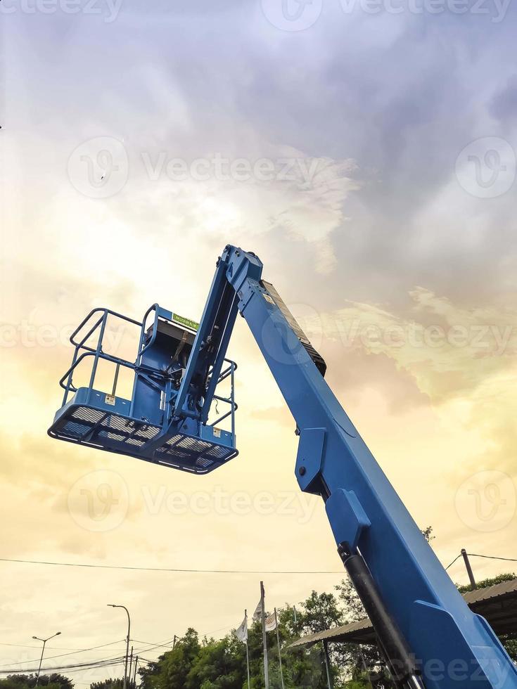 Manlift crane with platform lifting to the roof top of a building photo