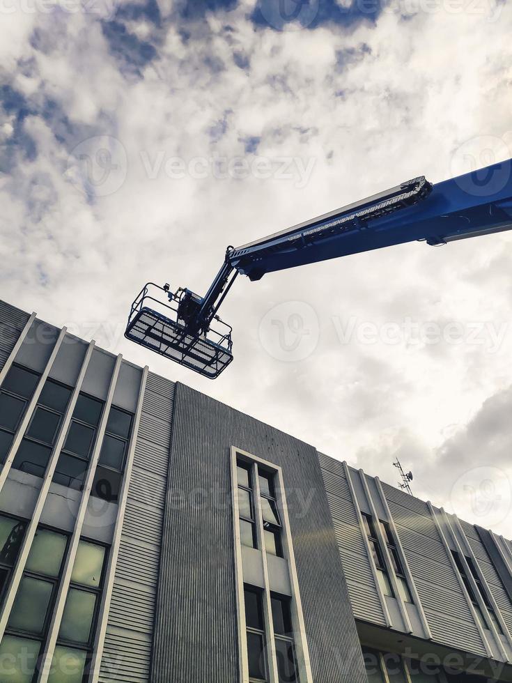 Manlift crane with platform lifting to the roof top of a building photo