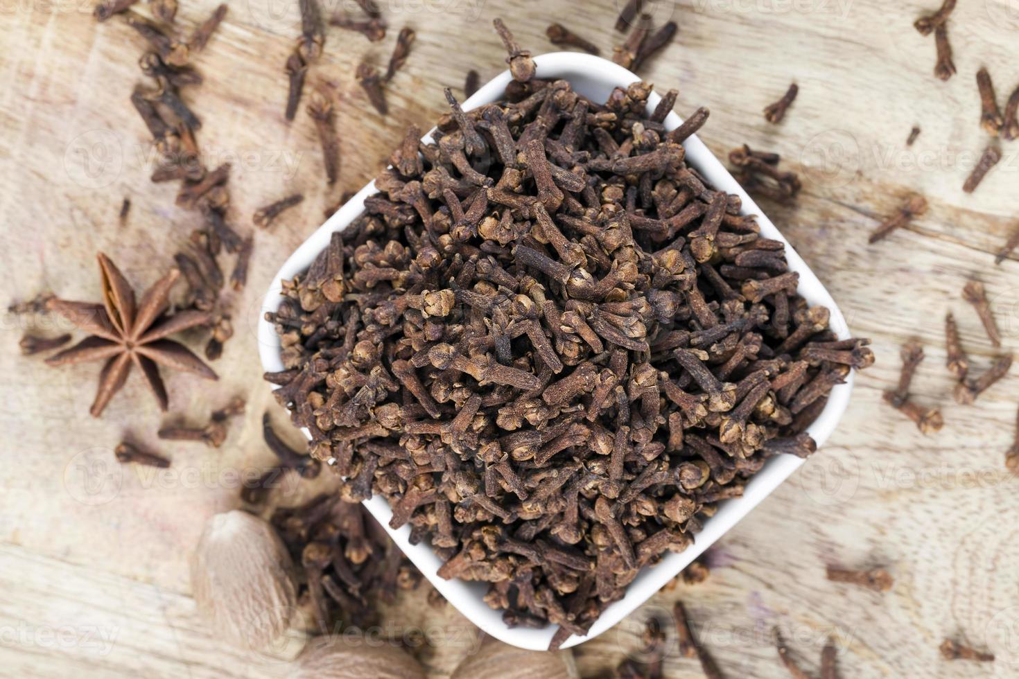 spices of cloves scattered on an old wooden table photo