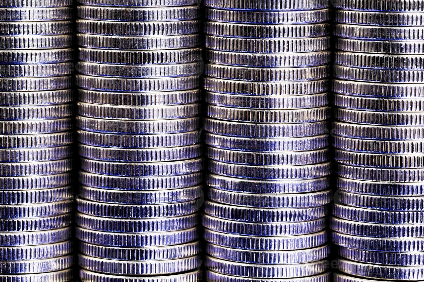 muchas monedas redondas de metal de color plateado iluminadas en azul foto
