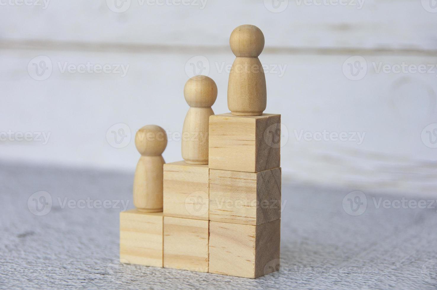 Wooden people figures on top of wooden blocks. Career growth concept photo