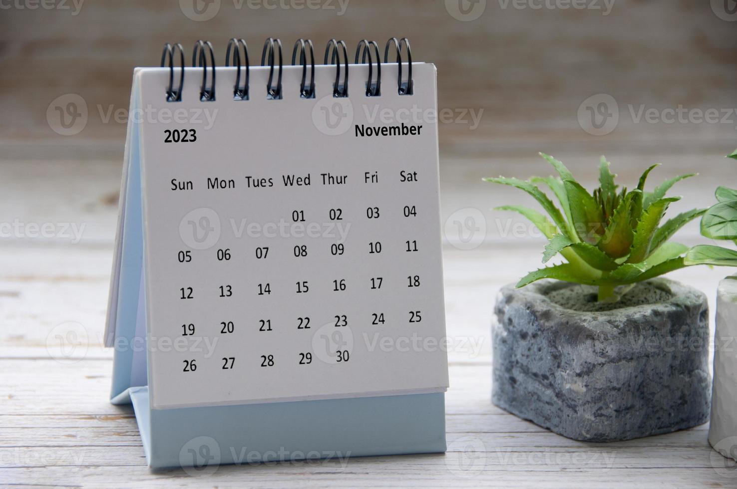 November 2023 white desk calendar on wooden table. Copy space photo