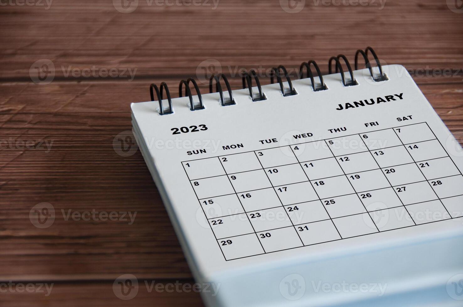 January 2023 white desk calendar on wooden table background. Calendar concept photo