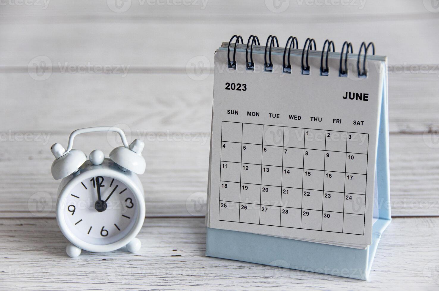 June 2023 white desk calendar on wooden table. New year concept and copy space photo