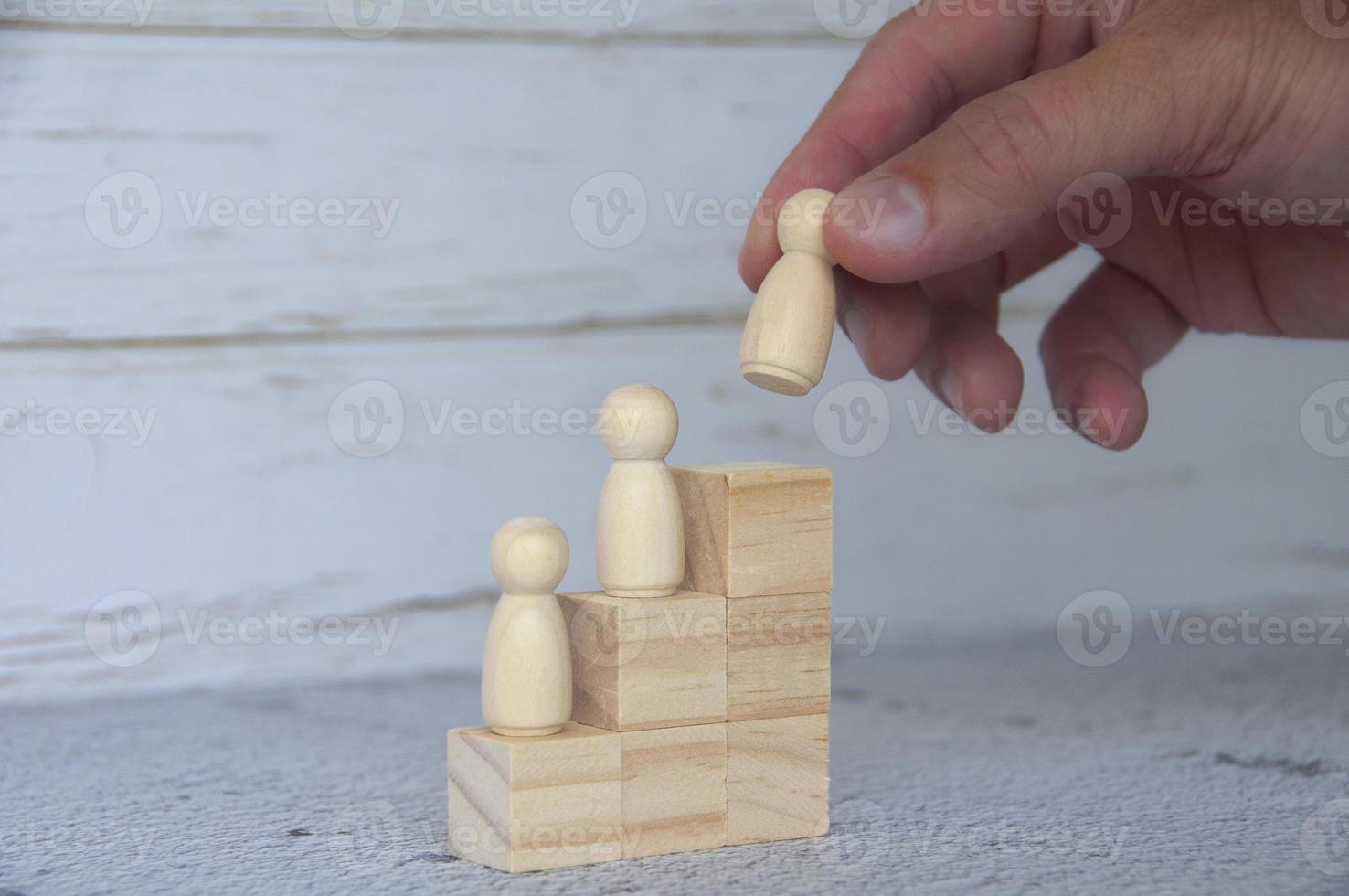 Hand putting wooden figure on top of wooden blocks. Career growth concept photo