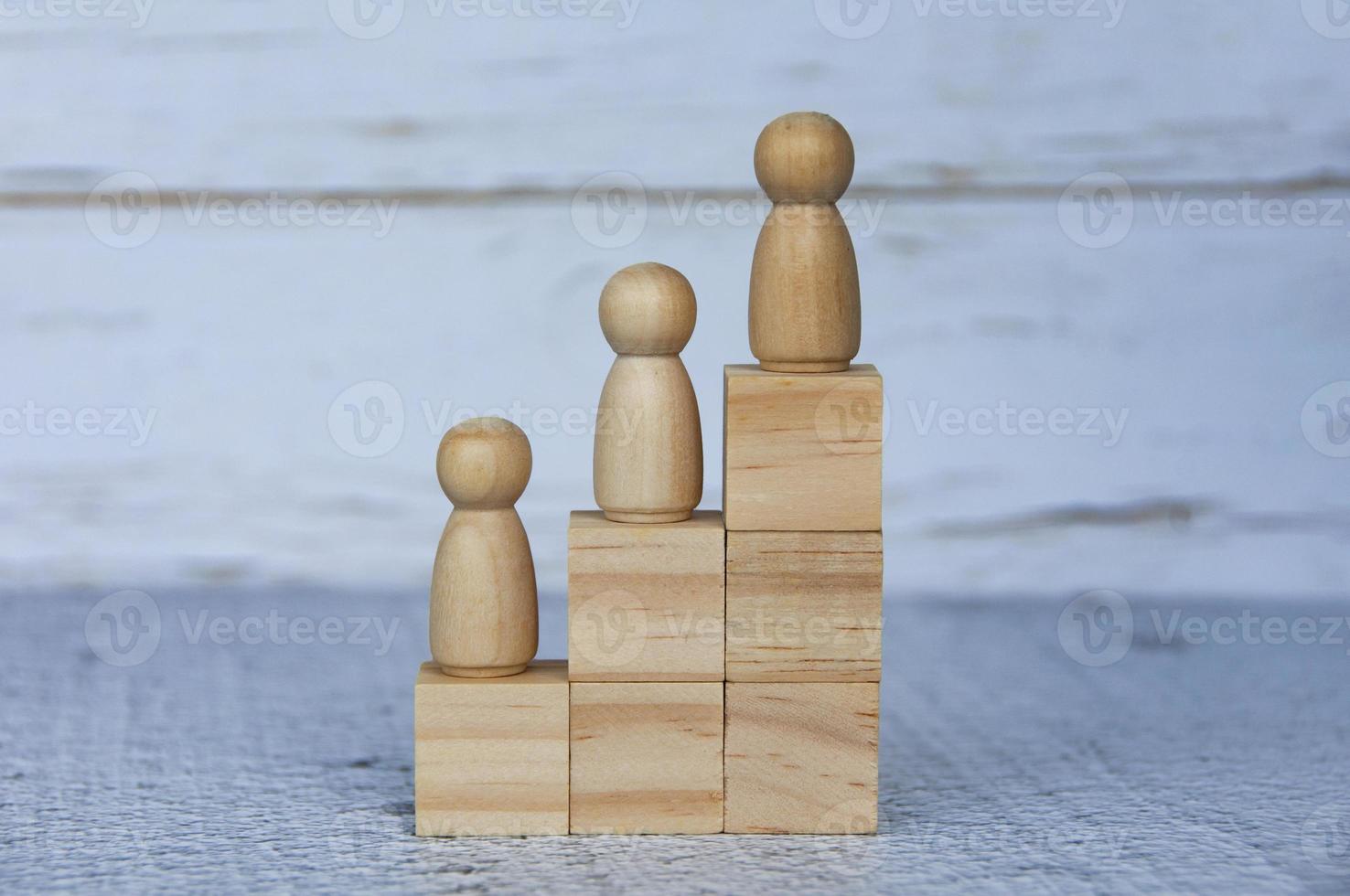 Wooden people figures on top of wooden blocks. Career growth concept photo