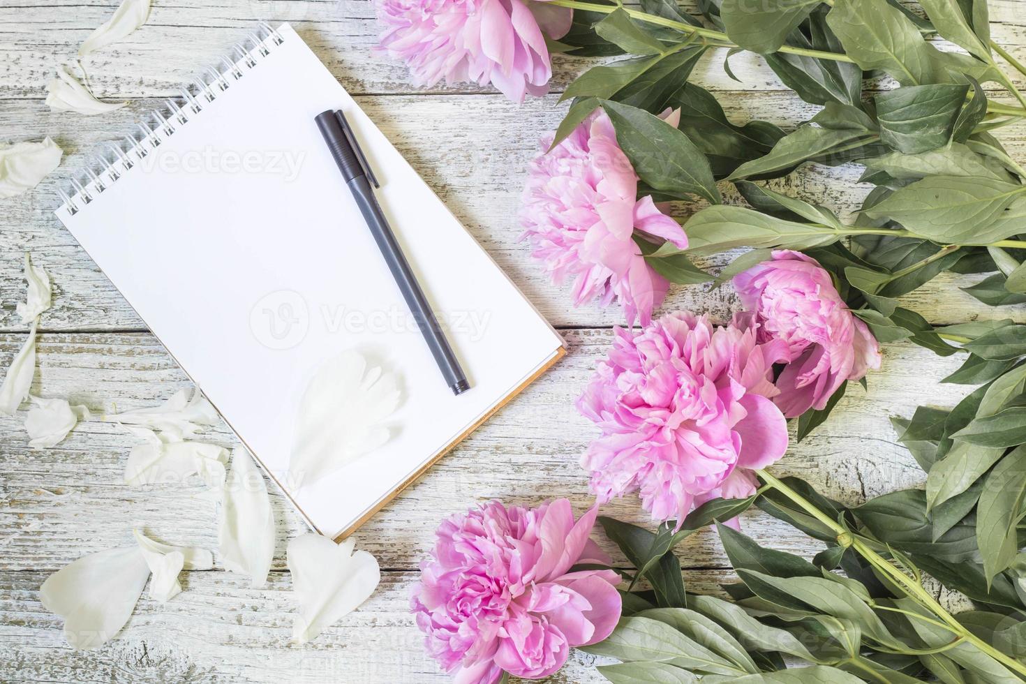 Open blank notepad, pen, and peony on the white wooden table. romantic flat lay. photo