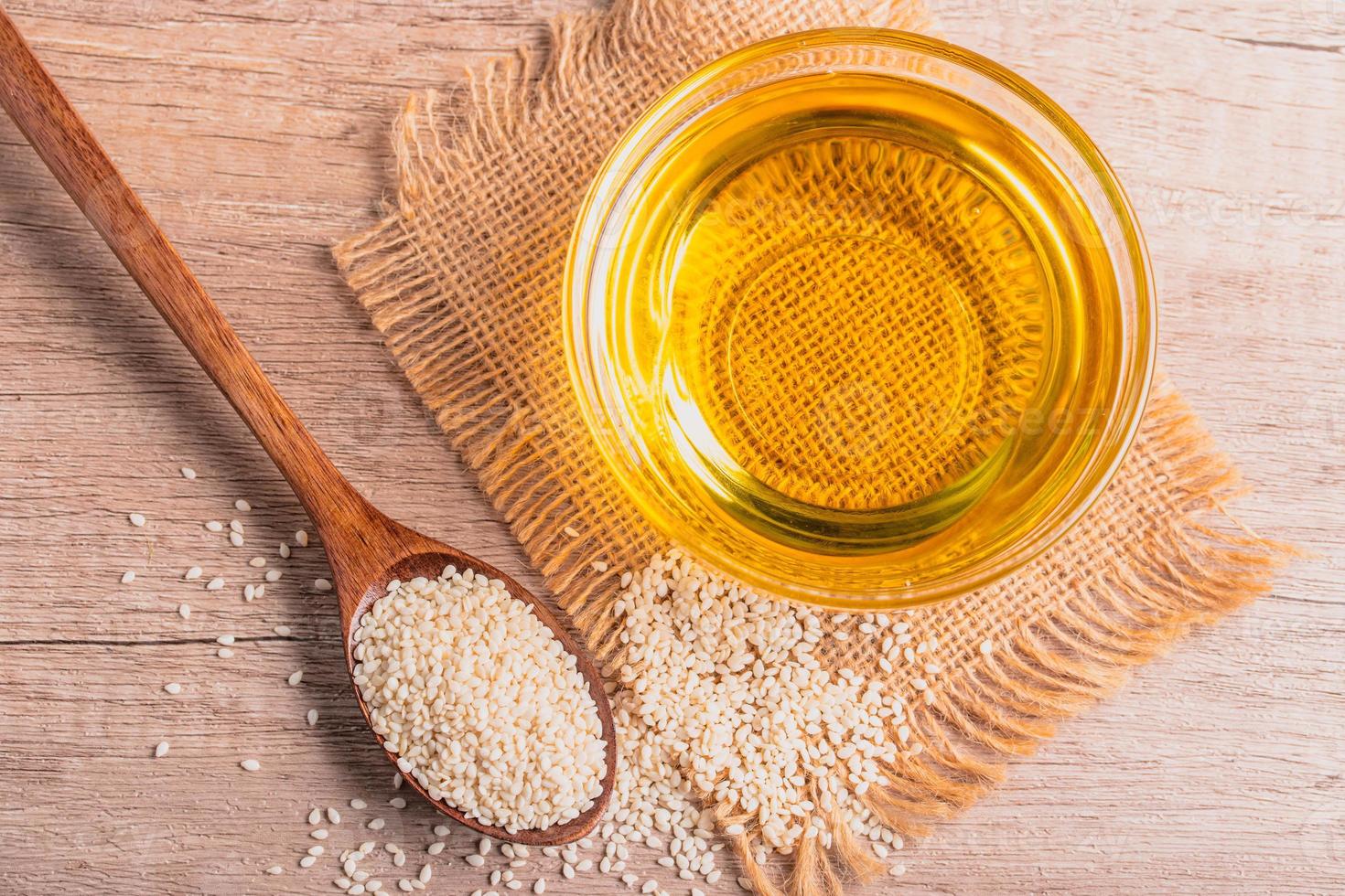 sesame oil in a bowl and white sesame seeds on wooden background photo