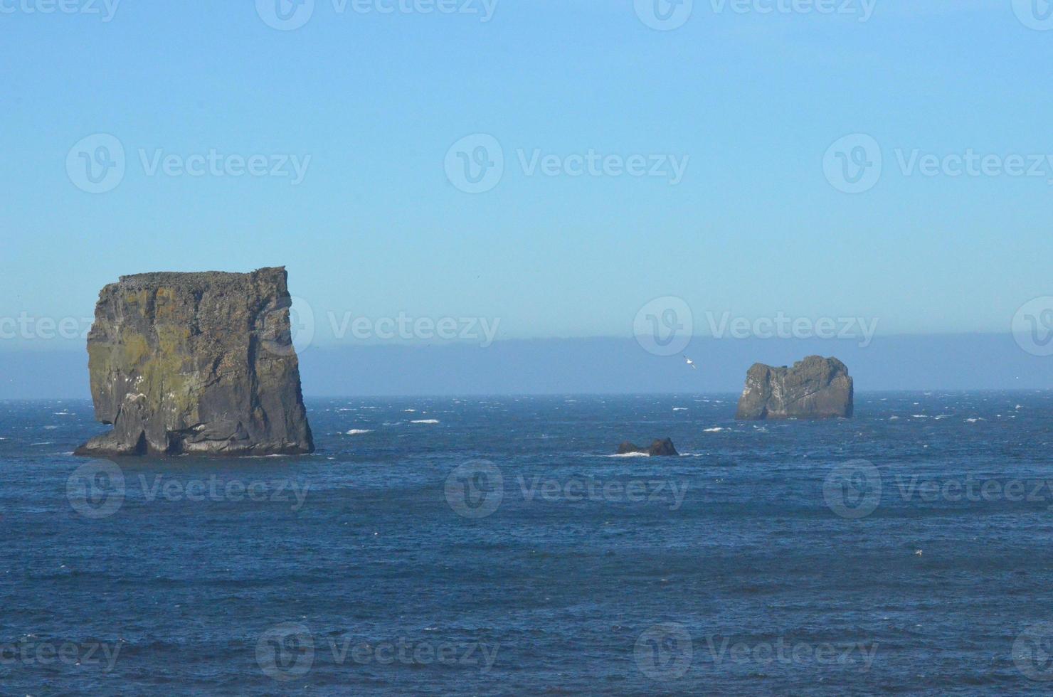 A pair of large rocks surrounded by beautiful blue waters photo