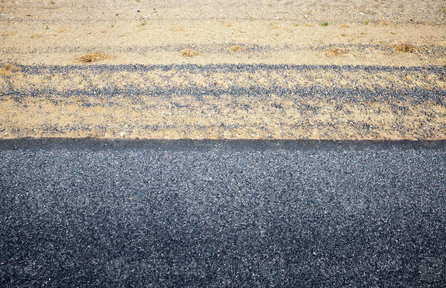 The edge of the asphalt road with the side of the road in asphalt, The side of the sand , top view photo