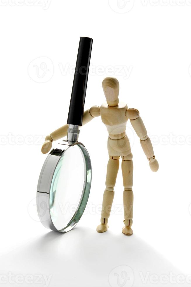 Wooden mannequin holding magnifying glass photo