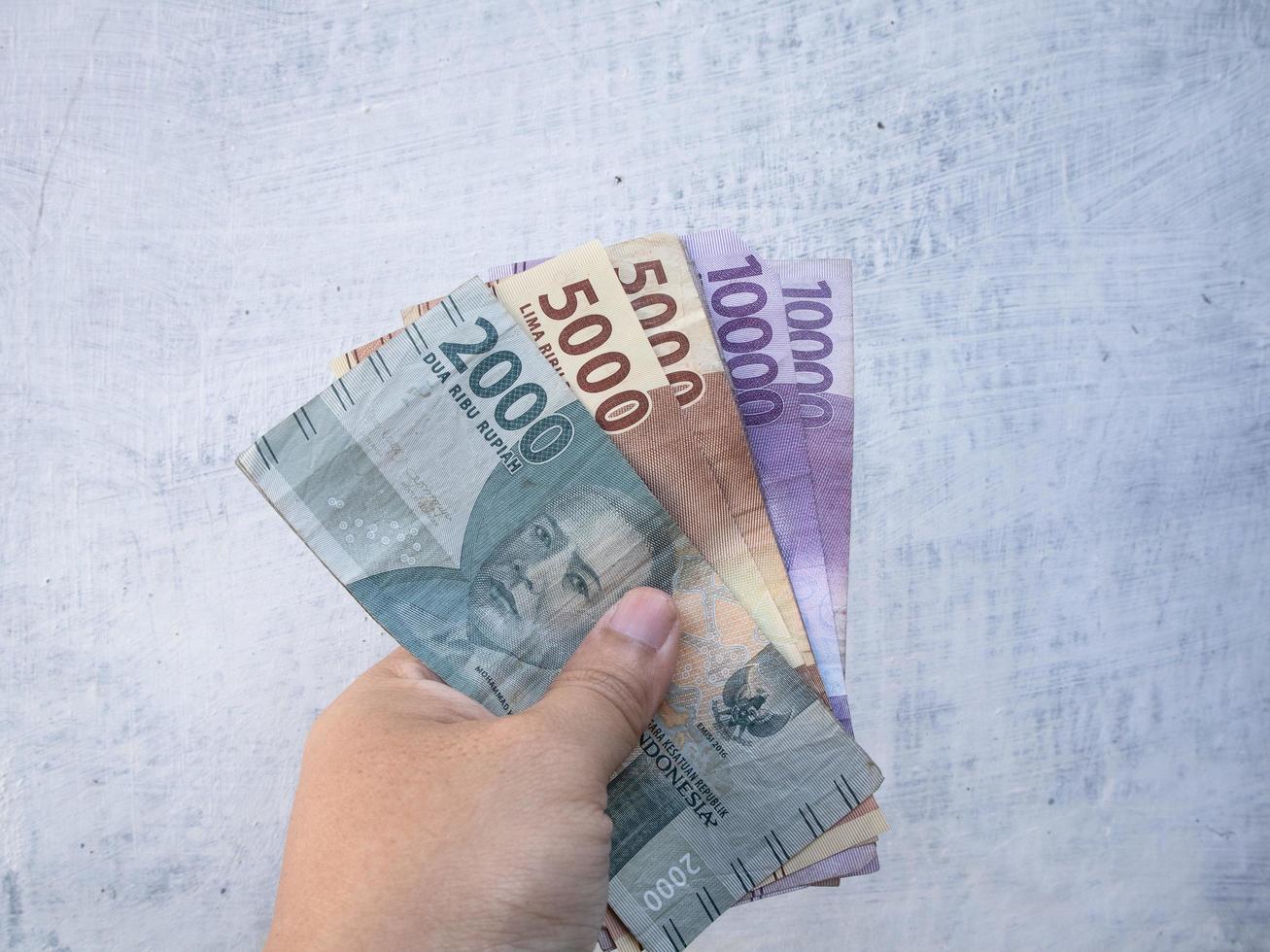 un hombre que sostiene un billete con una denominación nominal de 10000, 5000, 2000 rupias en moneda indonesia foto