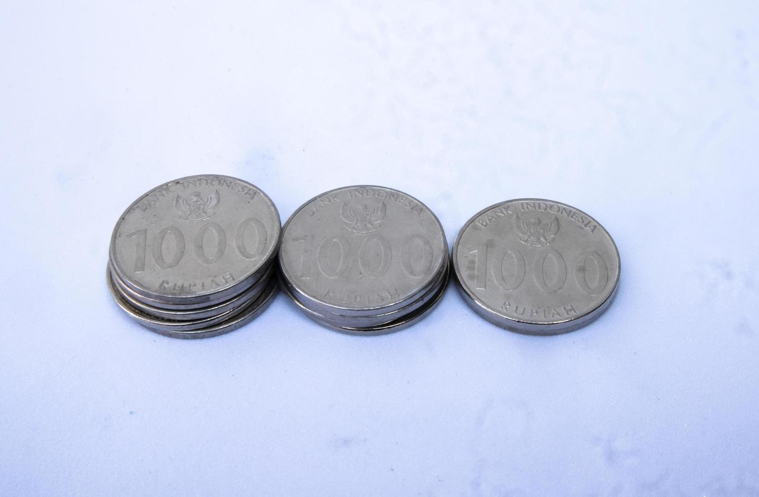 Close-up photo of 1000 rupiah coins, Indonesian currency neatly arranged in 3 stacks isolated on a white background