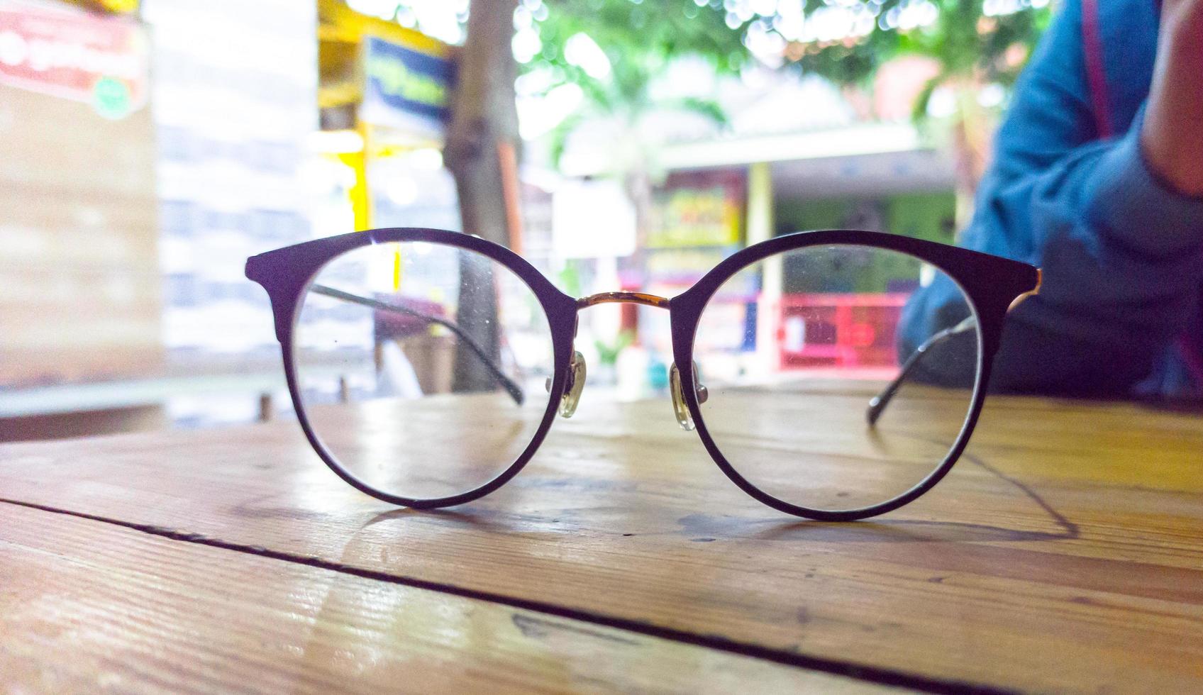 foto de primer plano de gafas de pie sobre una mesa de madera sobre fondo borroso