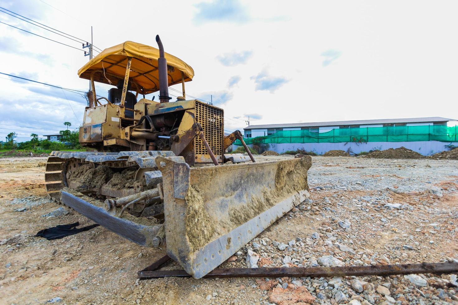 Bulldozer sobre orugas amarillo estacionado en un claro en preparación para la capa superior del suelo y un hermoso cielo azul en el fondo. el concepto de una excavadora prepara la capa superior del suelo para la construcción. foto