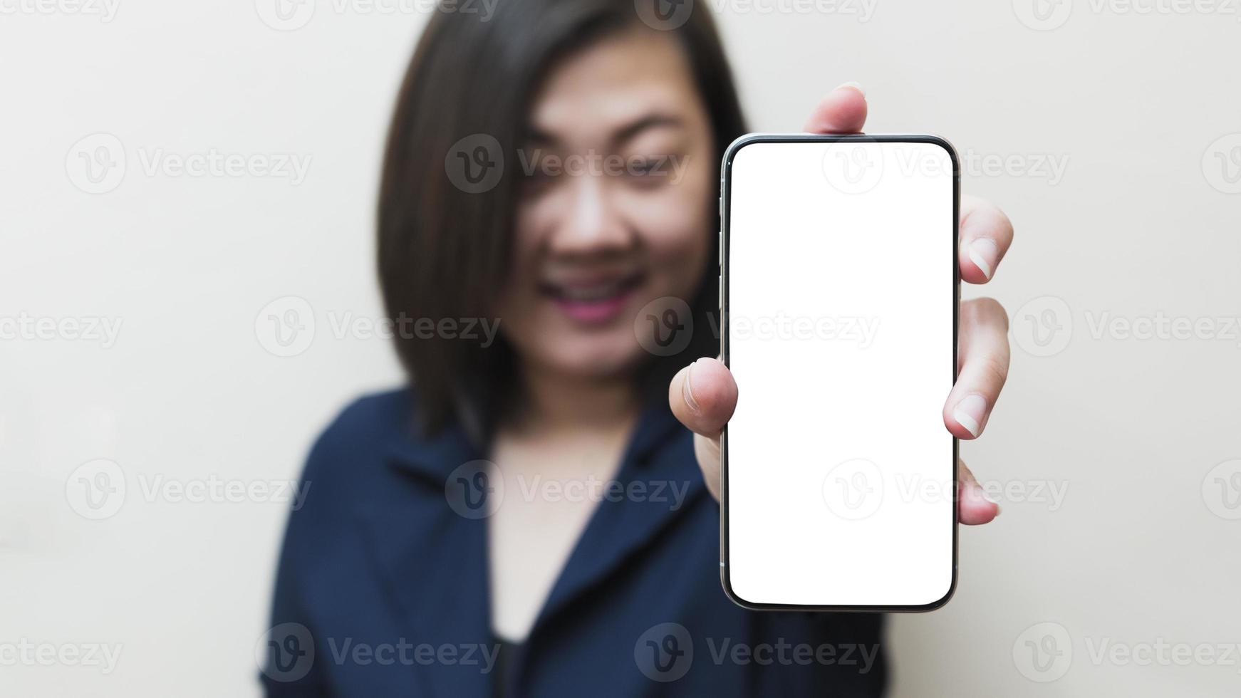 The left hand of a white woman showing a black mobile phone or cellphone and a white screen display for mockup content at an isolated or cutout white background. photo