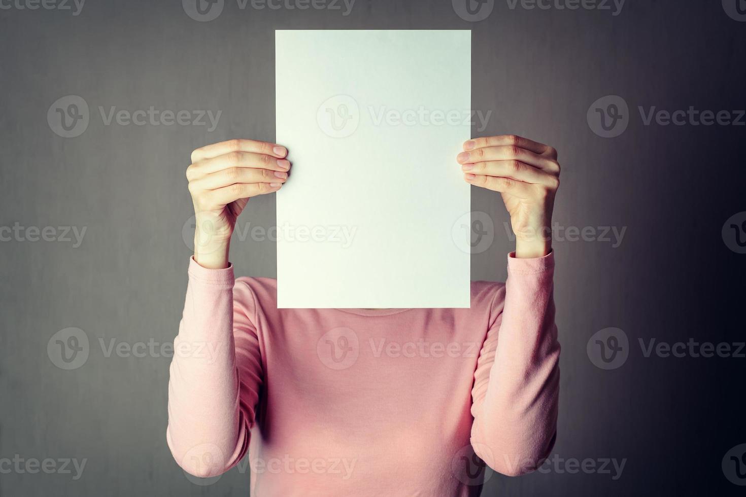 mujer anónima que cubre la cara con una hoja de papel blanco foto