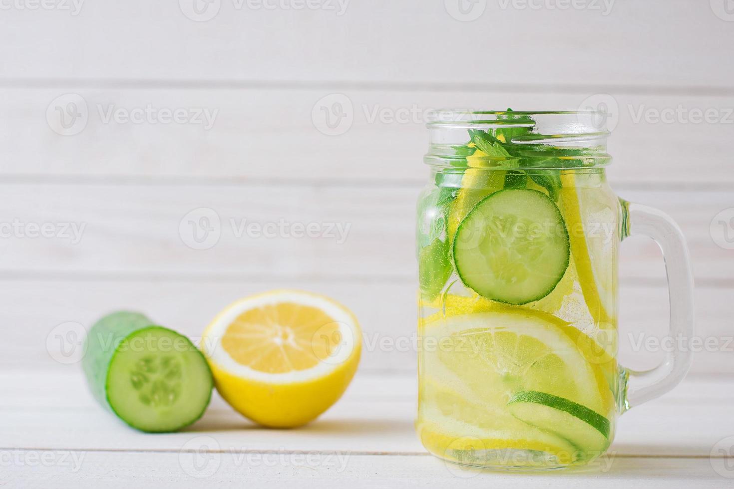 water with lemon and cucumber in a glass cup photo