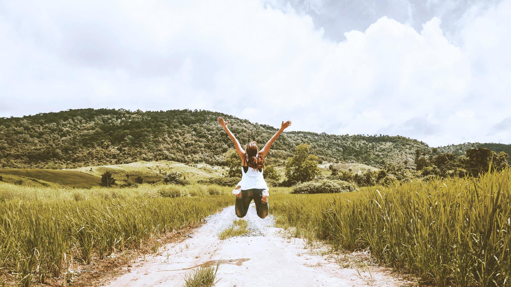 Asian women travel relax in the holiday. Jumping on the middle of the meadow road photo