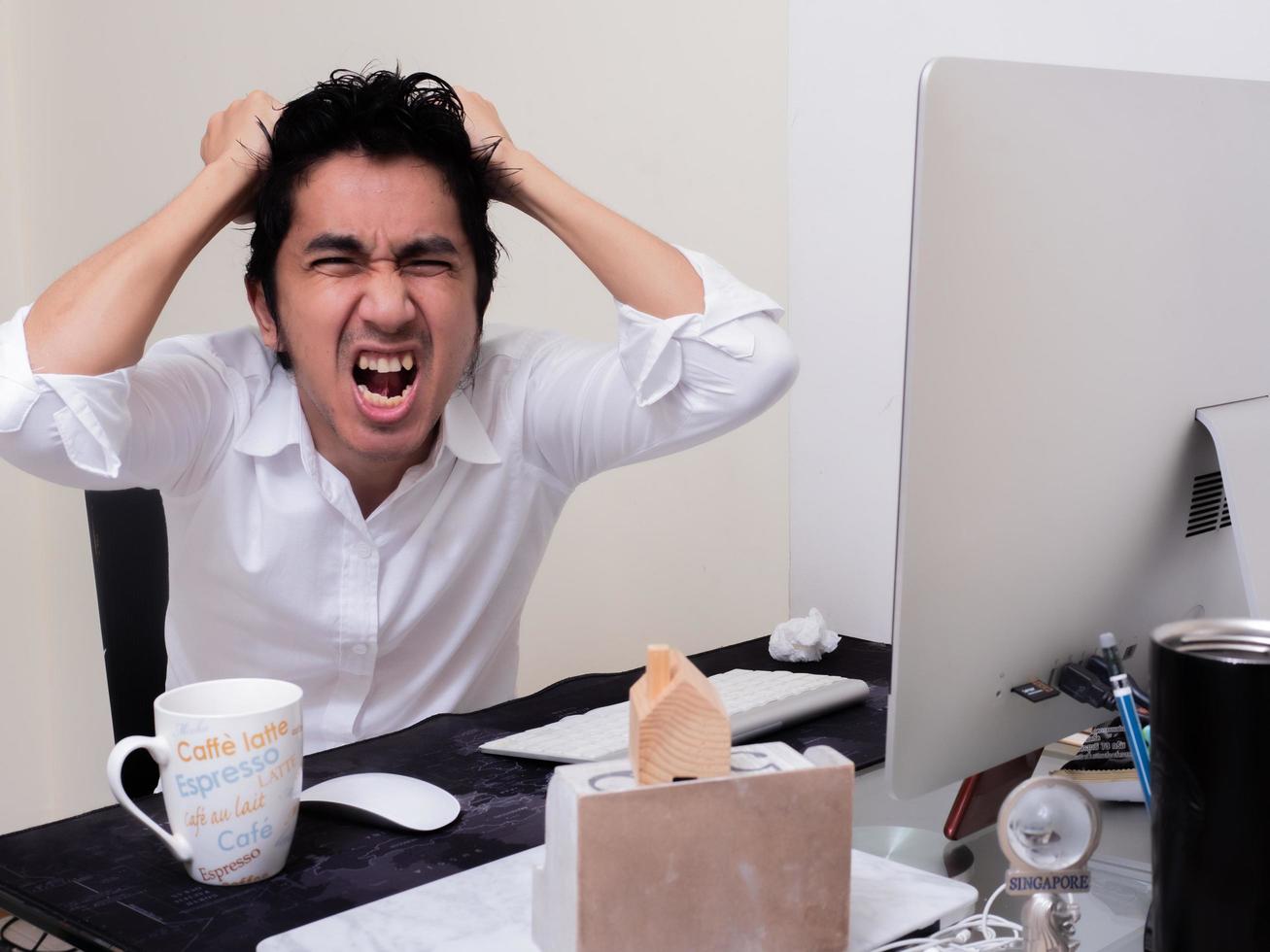 Serious Asian man is working with laptop in his apartment bedroom in concept of Work From Home and Work at Home photo