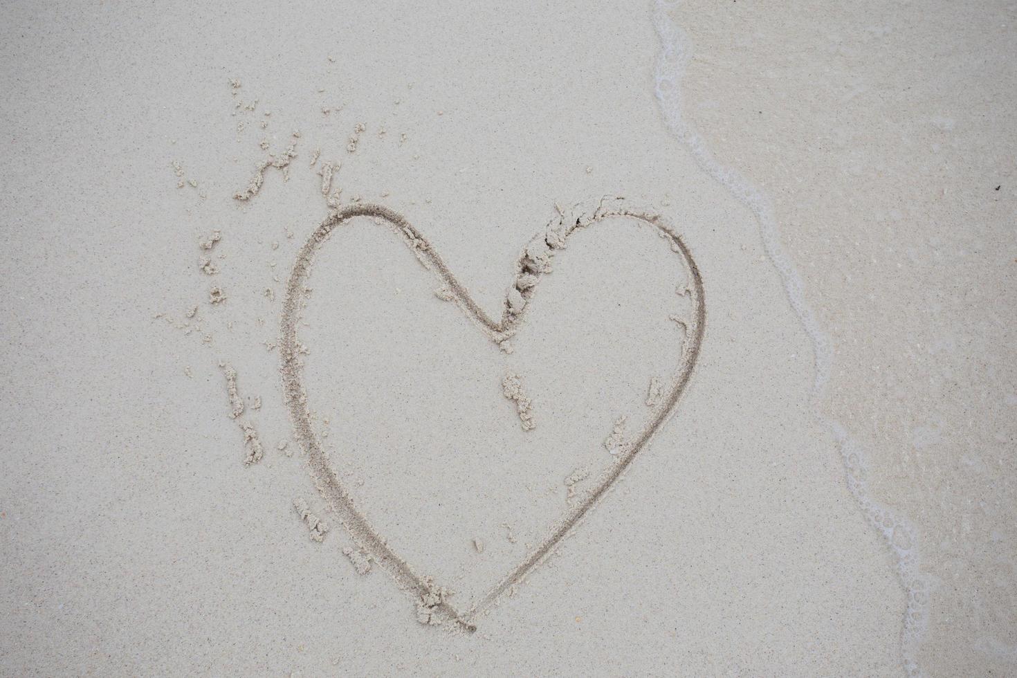 corazones dibujados en la arena de una playa foto