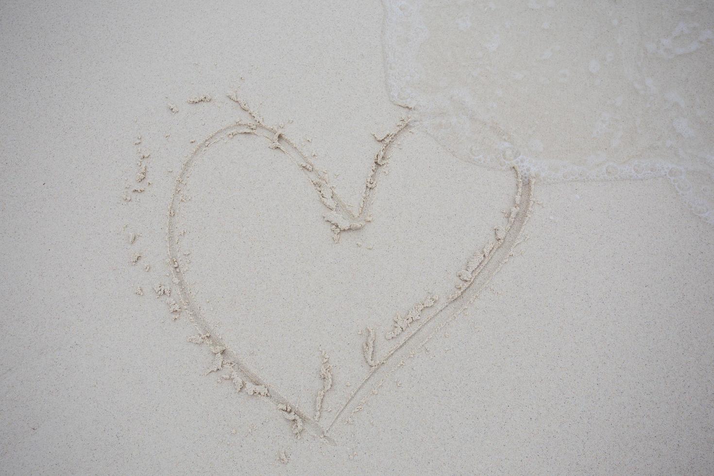 corazones dibujados en la arena de una playa foto