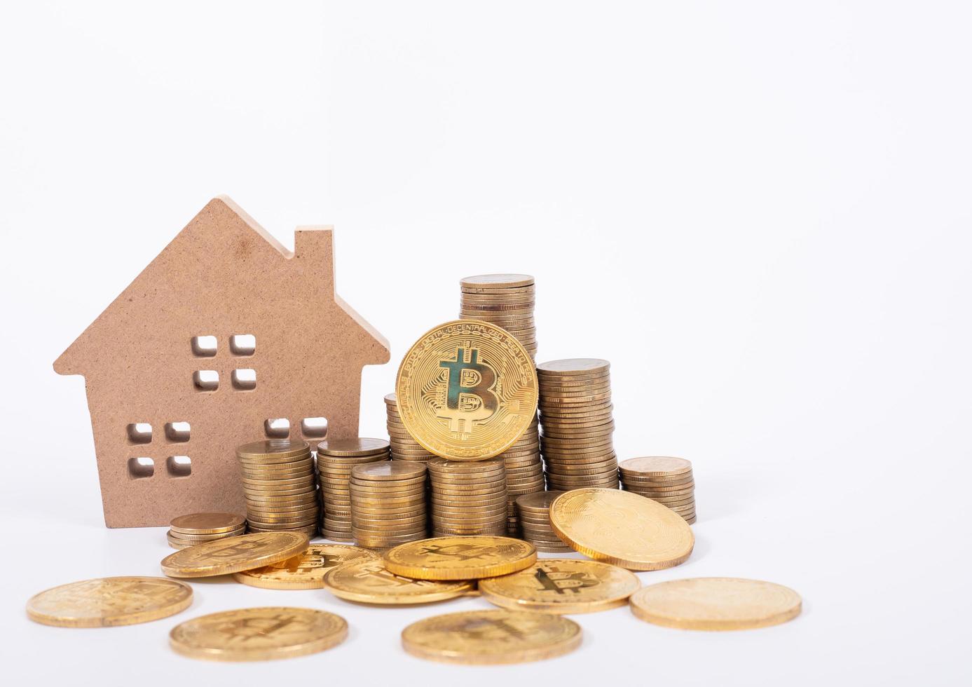 Buying and selling real estate for bitcoins concept with small cottage house and golnden metal bit coin. photo