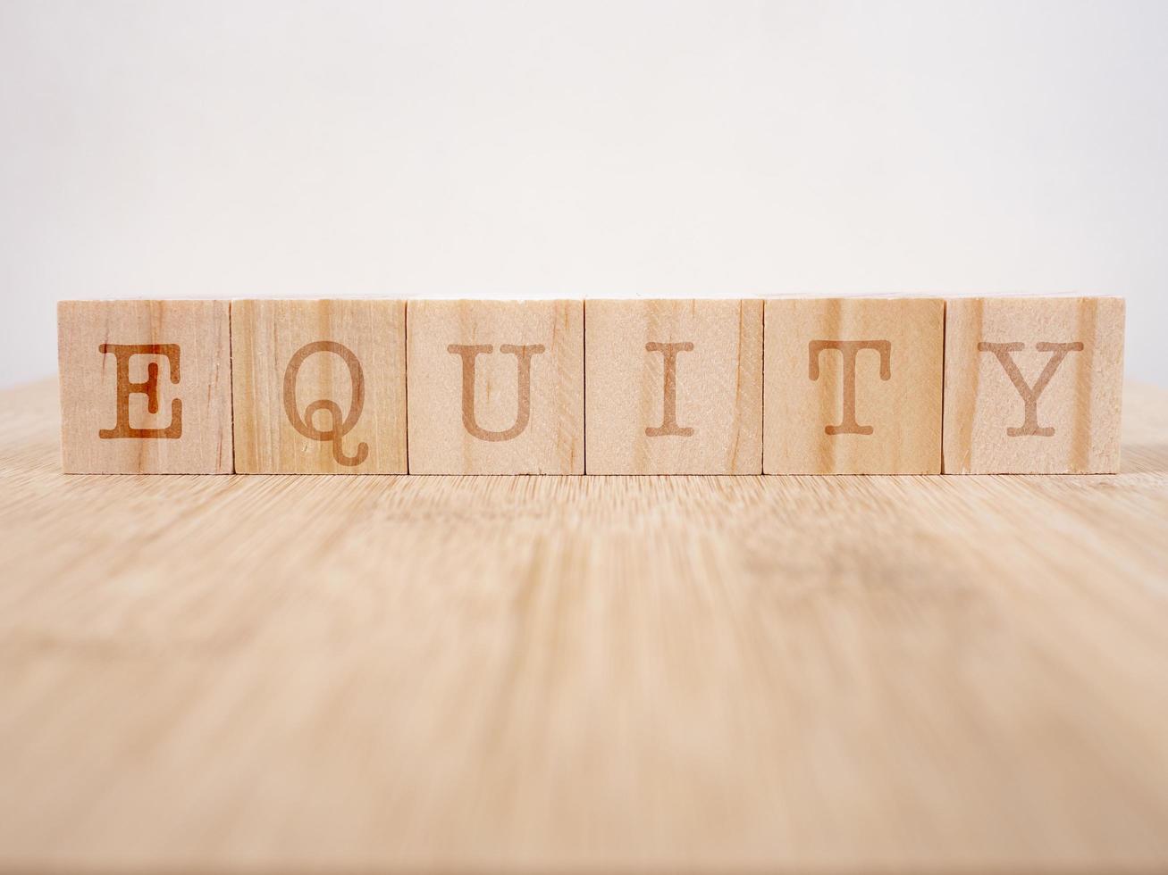 Letter block in word equity on wood background photo