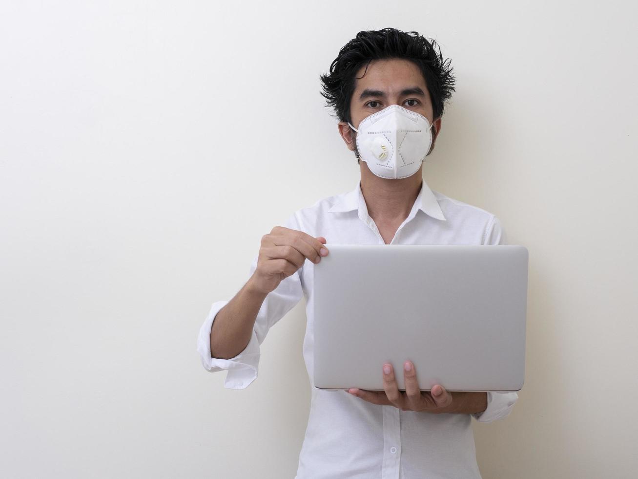 Business man in medical face mask works on laptop at home photo